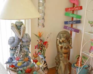 Coastal & Tropical Décor Collection A fun assortment of coastal, beach, and tropical décor perfect for a Florida room, beach house, lake home, vacation property, or anyone who loves seaside style. Featured items include: Matching pelican table lamps with nautical rope, netting, and marine details Colorful metal fish tabletop sculpture Large mother and baby manatee sculpture with aged bronze-tone finish Flamingo beach sign décor featuring whimsical beach-themed sayings Tropical floral arrangements and greenery Coastal accent pieces and nautical collectibles White metal display shelving Assorted beach-themed decorative accessories Mother & Baby Manatee Sculpture Beautiful large decorative sculpture depicting a mother manatee cradling her calf. Finished in an aged bronze-tone patina, this substantial piece captures one of Florida's most beloved marine mammals. A wonderful statement piece for coastal, tropical, lake house, beach house, or Florida-inspired décor.