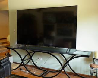 LG 86" Smart TV LG 86" Smart Television (Purchased Late 2024) Massive 86-inch LG Smart TV with ultra-thin bezel design and exceptional picture quality. Purchased new in late 2024 and lightly used. Perfect for home theater, sports viewing, gaming, or a media room. Includes original stand feet and remote control. Also available separately: Contemporary TV Console Table Modern black metal and glass media console featuring a distinctive curved geometric base design and tempered glass accent shelves. Coordinates with matching coffee and sofa tables offered elsewhere in the sale. Note: TV and console table sold separately unless otherwise marked at the sale.