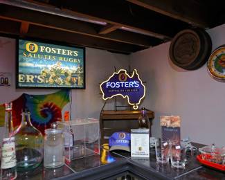 Vintage Beer & Neon Bar Collection Step back into the golden age of home bars and brewery memorabilia! This collection features an outstanding assortment of vintage beer advertising, illuminated signs, bar décor, and breweriana collectibles perfect for a man cave, game room, garage bar, or collector's display. Highlights include: Vintage Foster's Australian for Beer neon sign in the shape of Australia Framed illuminated Foster's Salutes Rugby advertising display Vintage Miller barrel-style wall sign Illuminated beer advertising wall clock Foster's promotional hat, glassware, and bar accessories Assorted vintage liquor bottles, decanters, and barware Beer-themed serving pieces and decorative collectibles Additional brewery and advertising memorabilia throughout the collection Whether you're a breweriana collector, neon sign enthusiast, or looking to outfit the ultimate home bar, this unique assortment offers plenty of conversation pieces and nostalgic charm.