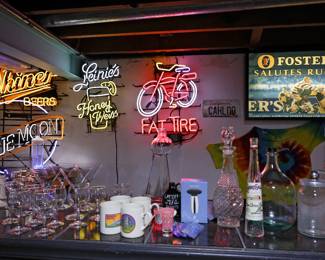 Neon Signs, Barware & Breweriana Collection Transform your game room, basement bar, garage, or man cave with this impressive collection of vintage neon advertising signs, breweriana, and bar accessories gathered over decades. Featured highlights include: Vintage Miller Beer neon sign Illuminated Leinenkugel's Honey Weiss neon sign Large Fat Tire Bicycle neon advertising sign Framed illuminated Foster's Salutes Rugby display Additional Foster's beer memorabilia and advertising pieces Assorted vintage glass decanters and liquor bottles Bar glasses, martini glasses, mugs, and entertaining pieces Decorative bar accessories and serving items California vanity license plate and assorted wall décor This collection comes from the estate of a longtime collector and entertainer who enjoyed creating the ultimate home bar experience. Whether you're looking for statement neon signs or unique breweriana collectibles, you'll find plenty to explore.