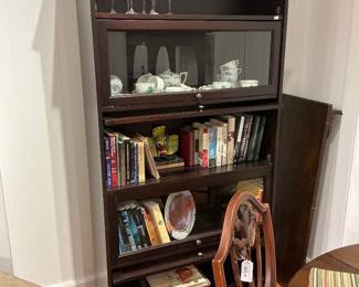 Description: A classic, traditional-style stackable barrister bookcase crafted in a rich mahogany finish. This multi-functional piece features a crown molding top and a total of five spacious tiers designed for showcasing literary collections, fine glassware, or decorative curios. Two of the central tiers feature signature glass-front lift-and-recede doors with small brass knobs, offering dust-free protection, while the remaining tiers provide open-shelf styling for easy access. Ideal for a sophisticated study, office, or dining area display. Estimated Dimensions: Width: 36" Depth: 12" Height: 72"