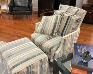 Transitional Striped Armchair and Matching Ottoman Set Description: A comfortable, transitional lounge chair and matching oversized ottoman set upholstered in a plush, multi-toned striped cut-velvet or chenille fabric. The textile pattern features a serene coastal palette of sage green, teal blue, cream, and taupe vertical stripes. The chair is designed with a gently sloping, painted cream wood exposed frame, a loose seat cushion, and coordinating plush back and accent throw pillows for maximum comfort. Both the Bergère-inspired chair and the rectangular ottoman are supported by square, tapered wooden legs finished in a matching off-white lacquer. Estimated Dimensions: Lounge Chair: 34" W x 36" D x 35" H Ottoman: 28" W x 22" D x 17" H