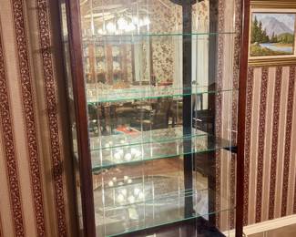 Dark wood lighted display/curio cabinet with mirrored back.