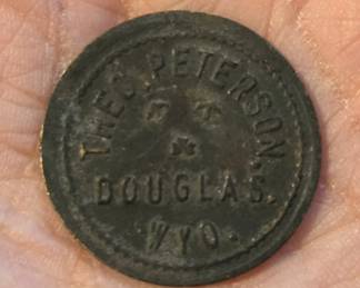 1890s Theodore Peterson Douglas Wyo Saloon Token.  Theodore Peterson arrived in Douglas, Wyoming in 1886.  This 1" metal token is for one drink from his saloon on Center Street in Douglas. His saloon served Union Pacific railroad construction workers (the railroad arrived in Douglas in 1886), many of whom were Irish, hence the two pickaxes and the Irish shamrock on the token.
