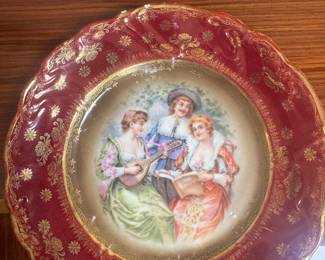 vintage porcelain plate features a central scene of people courting and is likely from the German maker Erdmann Schlegelmilch.