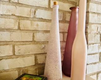 These slender, neutral-toned bottles are artisan-made vases featuring a cream glaze and textured finish