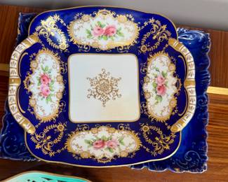 This antique porcelain dish is a Coalport dessert dish from the Regency era, circa 1810-1825. It features a deep cobalt blue scale border with heavy gold gilt embellishments and hand-painted floral panels.