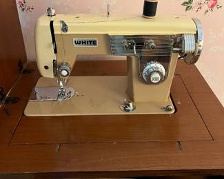 Vintage white sewing machine in cabinet