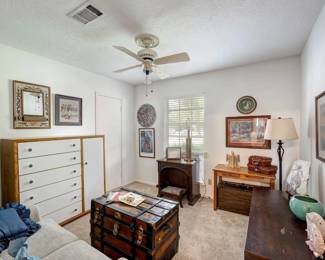 tall file cabinet, chest of drawers, antique desk, leather-strapped trunk, loveseat, wall art plus lots of decor