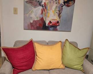 Neutral colored loveseat, colorful decorative pillows and large bull canvas art