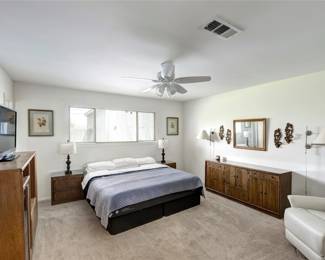 white leather recliner, TV, entertainment center, name brand dresser and nightstands, king bed, pair of lamps and an array of decorative items