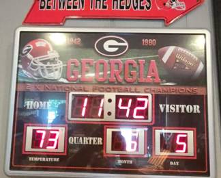 Team Sports America NCAA ScoreBoard Wall Clock featuring Georgia Bulldogs branding.The digital display shows time, temperature, month, and day.It is weather-resistant and can be used indoors or outdoors.