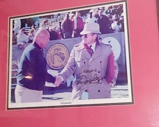 Framed historic photo autographed by Vince Dooley. Image captures two of the most iconic figures in Southeastern Conference (SEC) football history: Georgia Bulldogs head coach Vince Dooley & Alabama Crimson Tide head coach Paul "Bear" Bryant The Meeting: Pictured here are a 32-year-old Vince Dooley and a 51-year-old Bear Bryant shaking hands during the annual SEC football convention in Atlanta in January of 1965.