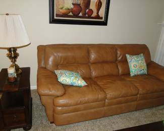 Large comfy leather sofa, a few throw pillows, and a side table with lamp and some art above