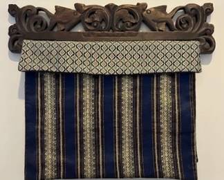 Handwoven Laos silk textile draped over a decorative carved wooden rod.