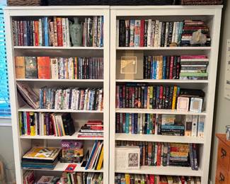 Two Pottery Barn white bookcases filed with books & Dvd's.