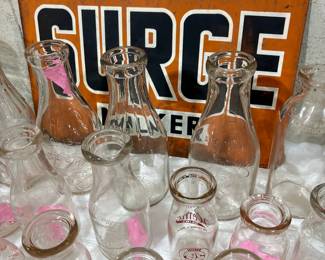 Assorted Vintage Glass Milk Bottles with SURGE Advertising Sign