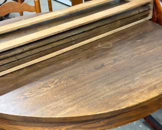 Close up of round oak table with 3 leaves.
