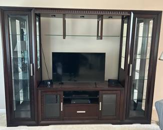 $350.00 Very contemporary and substantial, with glass door curio cabinets on both sides, glass shelving, built-in lighting, and a TV console center with glass door cabinets and a drawer. A few notes: This is a big heavy piece that requires disassembly and a truck - buyer is responsible for full disassembly and pickup with adequate help. 8' x7' and 18"inches deep Never been moved since delivery from store. "Pickup June 13th only — buyer must bring help and equipment for disassembly" Will include 30" TV for additional $50.