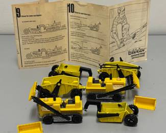 This is a set of vintage 1970 Mattel Hot Wheels Sizzlers Earthshakers toys, specifically featuring the Ground Hog dozer with various construction attachments; the set includes yellow bulldozers, detachable scrapers, dumpers, and a hitching bar for connecting different units.