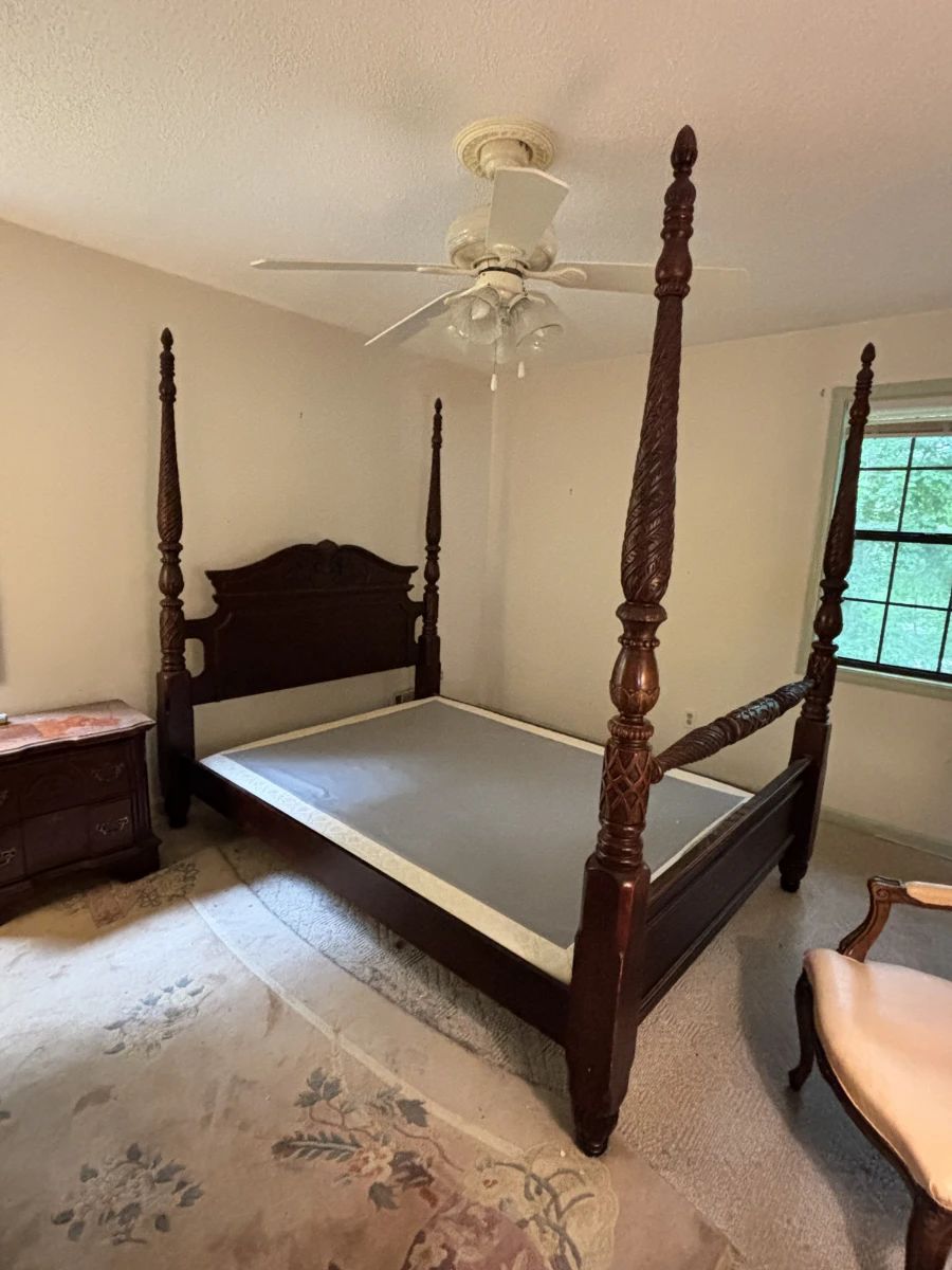 Dramatic queen-size four-poster bed in dark mahogany with heavily carved and rope-twist posts topped with pineapple finials. Carved arched headboard with scrollwork detail. Traditional American Colonial/Chippendale style. Very substantial and visually impressive piece. No mattress.