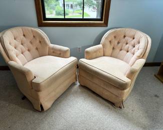 Matched pair of barrel-back club chairs with button tufting, cream/blush woven fabric, and low-profile arms. Mid-century style, appear to swivel. Fabric shows age and some discoloration but no obvious tears visible.