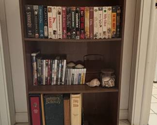 Assorted VHS Tapes, DVDs, Books, and Decorative Items on a Wooden Bookshelf