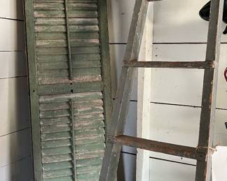 Antique shutters made into a hinged screen and various ladders in garage