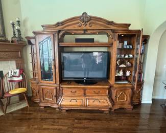 The AICO Tuscano Entertainment Center by Michael Amini features ornate Tuscan-style carvings and antique tarnished brass hardware.