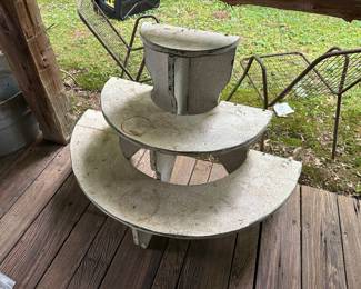antique white, tiered plant stand features a half-moon design with distressed wooden paint.
