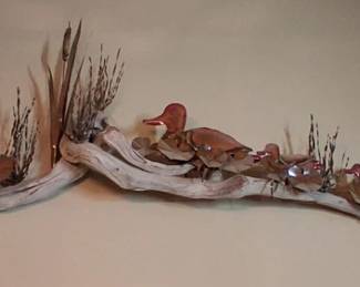 driftwood sculpture resembles rustic folk art, featuring carved wooden ducks arranged on a natural branch.