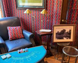 Another view of the leather chair and ottoamn, black jack table, round metal tables with glass tops, brass floor lamps, framed Oakland Hills comerative prints and more