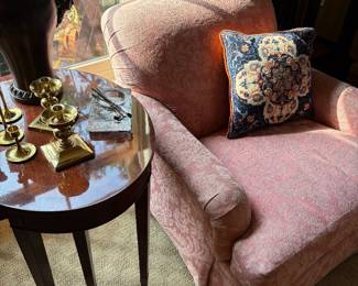 Another view of the oval nesting table and brass and metal candle holder and vase, and relaxed armchair
