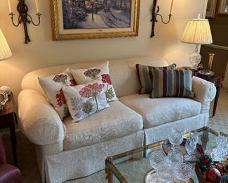 Ivory "linen' sofa, brass and glass (1" thick) coffee/cocktail table, "Village Christmas" lithograph by Thomas Kincade, pair of wall sconces for tapper candles