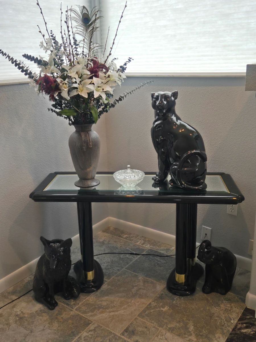 Black and glass couch table with ceramic cats and a flower arrangement