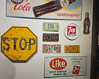 Collection of Vintage Advertising Signs and License Plates including Faygo Cola, STOP, 7UP, and Coca-Cola