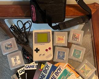 Nintendo Game Boy classic handheld console, model DMG-01, includes official carrying case with pink “GAME BOY” branding. Games included: Tetris, Mortal Kombat, The Legend of Zelda: Link’s Awakening, Final Fantasy Legend II, Final Fantasy Adventure, Madden NFL ‘96, Nintendo World Cup, Nemesis.
