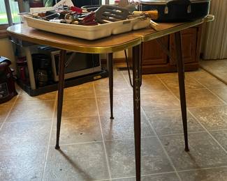 Vintage 1950-60s drop leaf dining table features a wood grain Formica laminate top and slender, tapered legs with brass accents