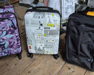 Lot 43: Three rolling suitcases: purple floral, cityscape white, and black