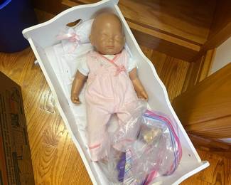 JC Toys Berenguer doll nestled in a white doll bassinet