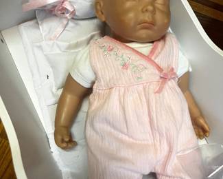 JC Toys Berenguer doll nestled in a white doll bassinet