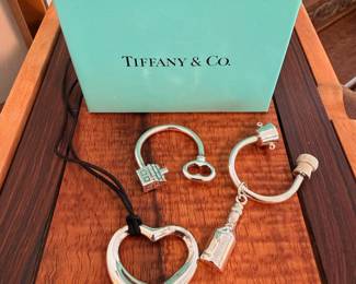Tiffany & Co. sterling silver Elsa Peretti ‘Open Heart’ pendant on black cord, champagne bottle keyring and ‘House’ keyring.  All items come with Tiffany & Co. boxes