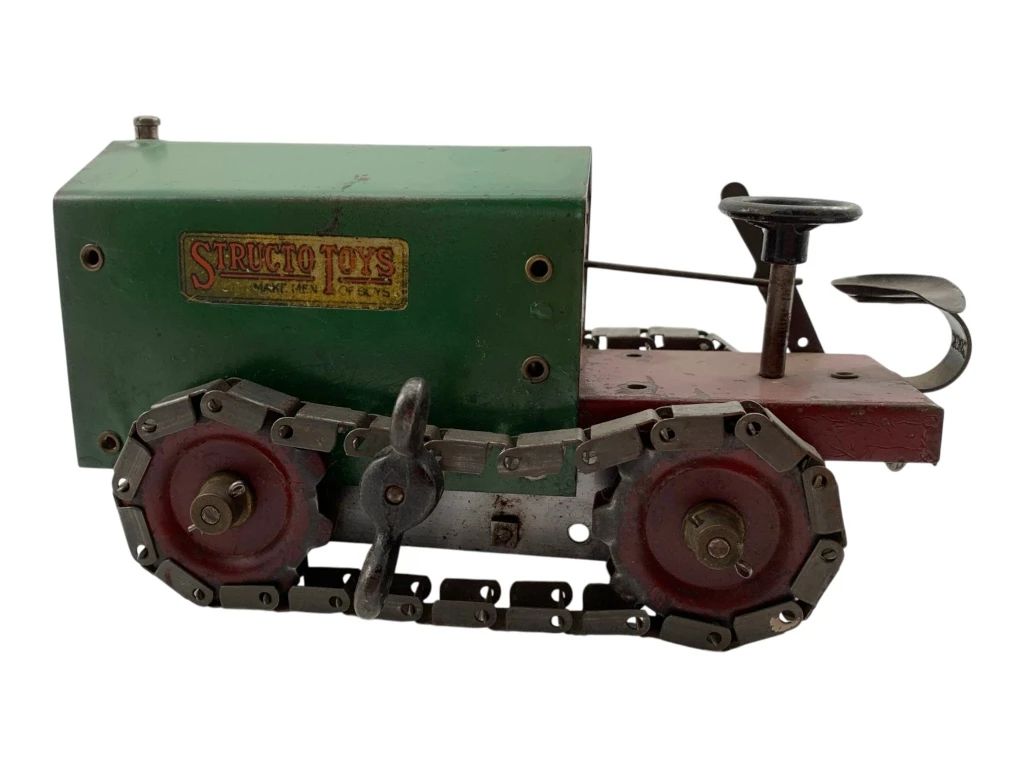 1 - Structo Toys Wind Up Tractor 3"x8.25"x4" (Description): Structo Toys wind up tractor measuring 3" x 8.25" x 4". This vintage pressed steel toy features a green engine compartment with the original Structo Toys decal, a red operator's platform with steering wheel and seat, and metal caterpillar tracks with red wheel hubs. The wind-up mechanism powers the treads for motion.