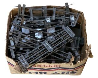 1097 - Box Lot O Scale Train Tracks (Description): A box lot of O scale train tracks. The collection includes multiple sections of metal track pieces with rail ties and connector plates, suitable for model railroad layouts. The tracks show signs of age and use consistent with vintage model train accessories.