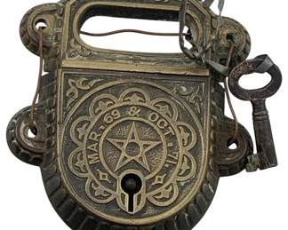 614 - Vintage Iron Deco Padlock w/Key 5"x3.5" (Description): Vintage iron Art Deco padlock with key. The lock features ornate decorative detailing and patent dates. Measures 5 inches by 3.5 inches.