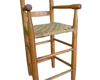 29 - Child's Ladderback High Chair w/ Woven Seat (Description): Vintage child's wooden ladderback high chair featuring a woven rush seat. This rustic piece has turned ball finials atop the back posts, rounded arm rests, and a sturdy stretcher base construction. The chair displays a warm natural wood patina consistent with age and use. Measures 32 1/2" x 16" x 13".