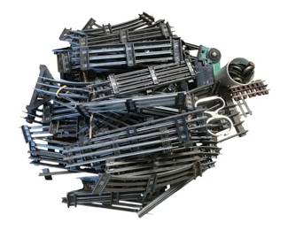 825 - Lot O Scale Model Train Tracks (Description): A large lot of O scale model train tracks. This collection includes numerous straight track sections, curved pieces, and various switches or turnouts. The tracks appear to be metal construction in a dark finish, suitable for O gauge model railroad layouts. A substantial quantity for building or expanding a model train setup.