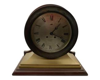 63 - Spaulding & Co Chicago Ships bell Clock (Description): Spaulding & Co Chicago ships bell mantle clock featuring a wood and brass construction. The clock displays a silver-toned dial with Roman numerals and is housed in a dark round case mounted on a brass and wooden stepped base. Measures 13 inches by 14inches by 6.5 inches. Used as is electric/electronic/mechanical item. No guarantee all components, untested.
