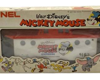 834 - Lionel Mickey Mouse Express Caboose O Scale (Description): Lionel Walt Disney's Mickey Mouse Express caboose in O scale, presented in its original box. The caboose features a white body with red roof and base, decorated with Mickey Mouse graphics and "Mickey Mouse Express" lettering. The box displays colorful illustrations of classic Disney characters including Donald Duck, Daisy Duck, Pluto, Dumbo, and Minnie Mouse. Marked with 1977 Walt Disney Productions copyright. Car number