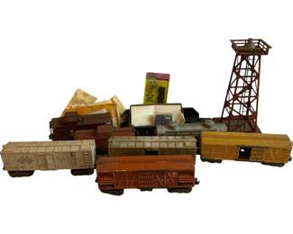1169 - Lot O Scale Trains w/ Freight Cars & Tower (Description): Lot of O scale model trains and accessories. The collection includes various freight cars such as livestock cars, boxcars, and a refrigerated rail car, along with a locomotive. Also included is a metal observation tower and additional accessories. The cars show vintage construction with painted metal bodies. Individual cars measure approximately 3" x 8.5" x 2". Shows overall wear consistent with age and play.